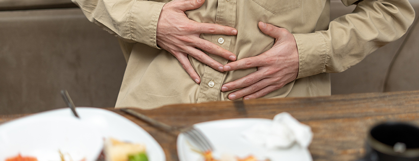 Man sitting after meal holding stomach with mild bloating discomfort after eating