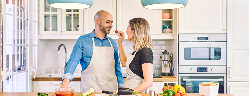 Mature couple preparing a healthy meal together in a bright kitchen with fresh vegetables and colorful ingredients.